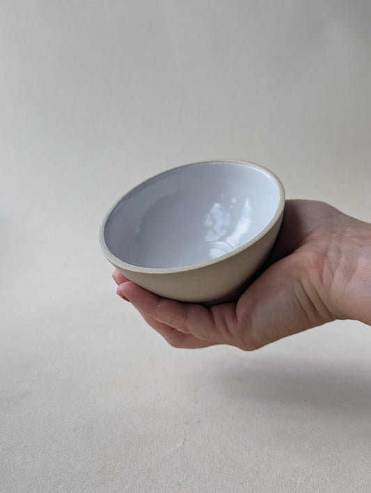 One handmade stoneware snack bowl held in a hand demonstrating the compact size.