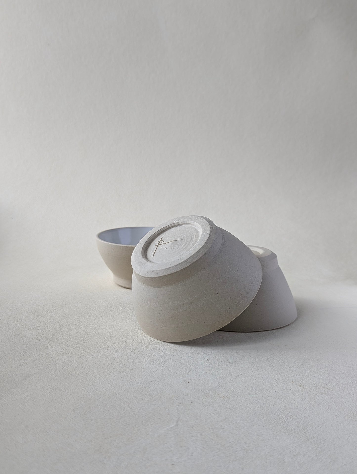 Two handmade stoneware snack bowls stacked upside down to demonstrate the beautiful bottom detailing and raw exterior.