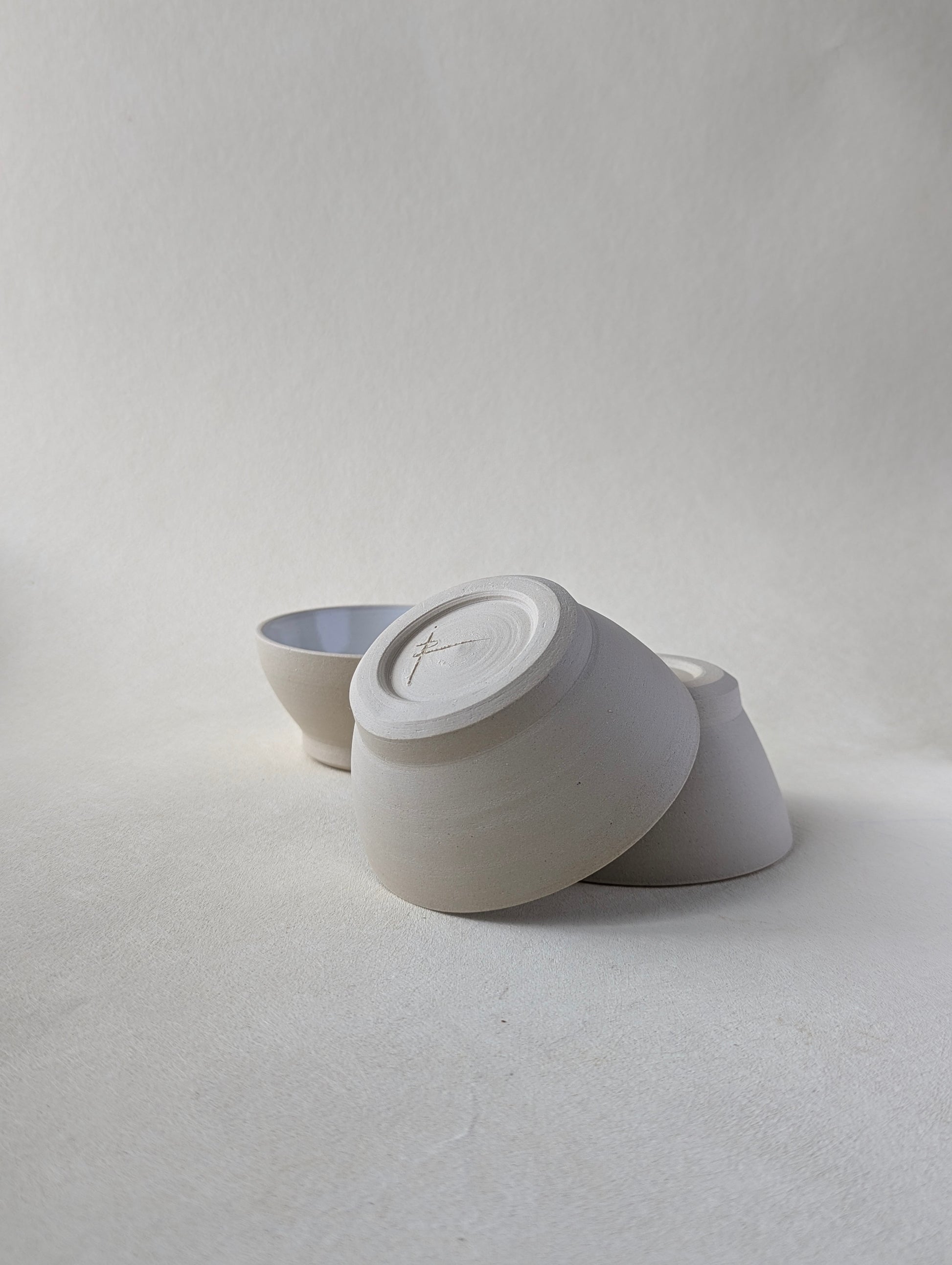 Two handmade stoneware snack bowls stacked upside down to demonstrate the beautiful bottom detailing and raw exterior.
