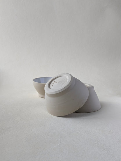 Two handmade stoneware snack bowls stacked upside down to demonstrate the beautiful bottom detailing and raw exterior.