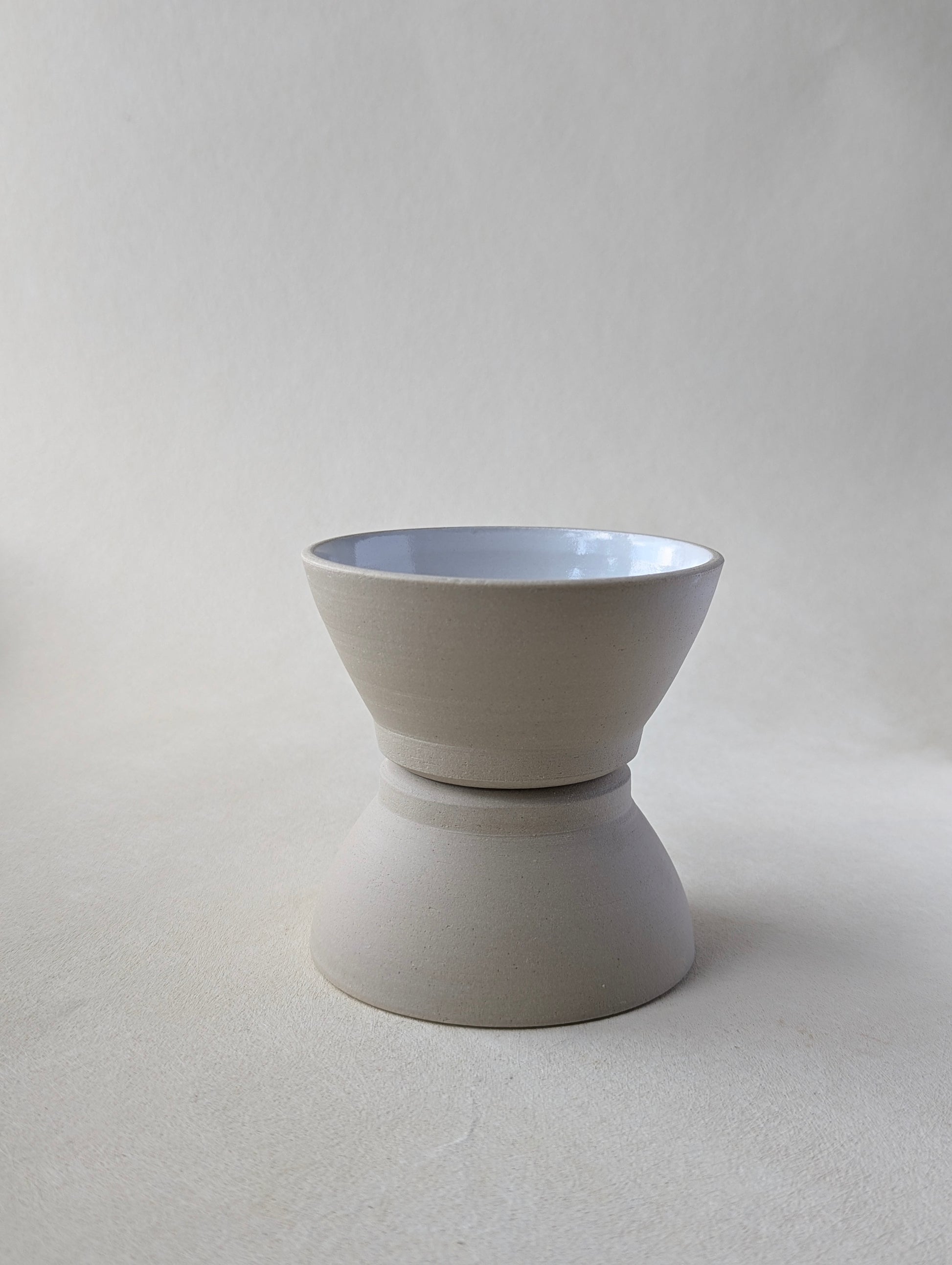 Two handmade stoneware snack bowls stacked, one upside down to demonstrate matching base size and raw exterior.