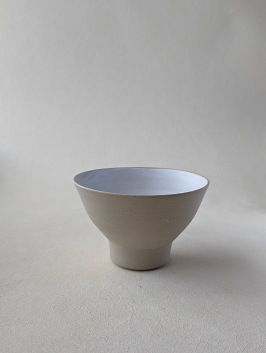 Side view of a handmade stoneware snack bowl with a matte white interior and raw exterior finish.