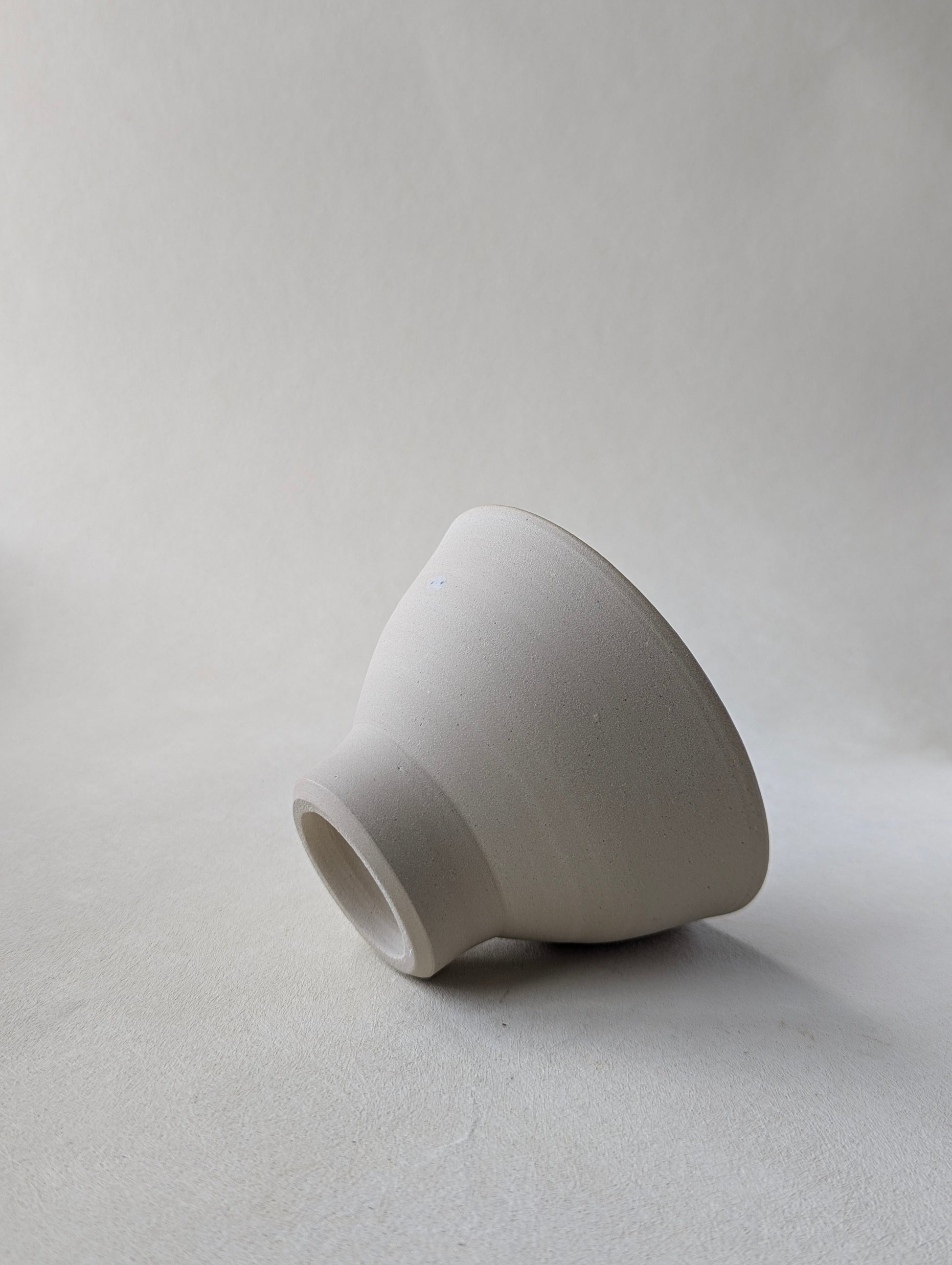 One handmade stoneware snack laying on the side to demonstrate the raw exterior and beautiful bottom detailing.