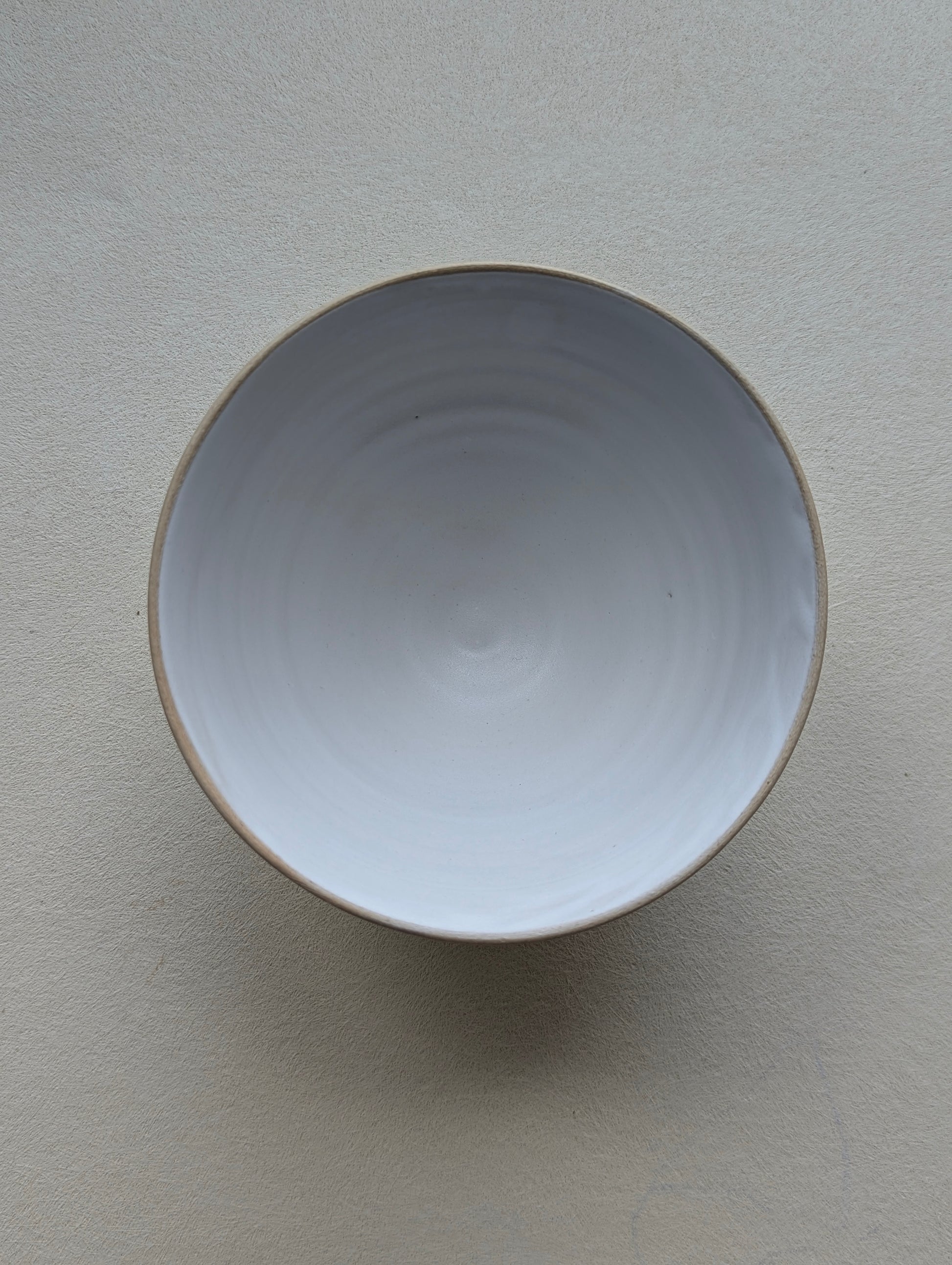 Top view of a handmade stoneware snack bowl, highlighting the matte white glazed interior.